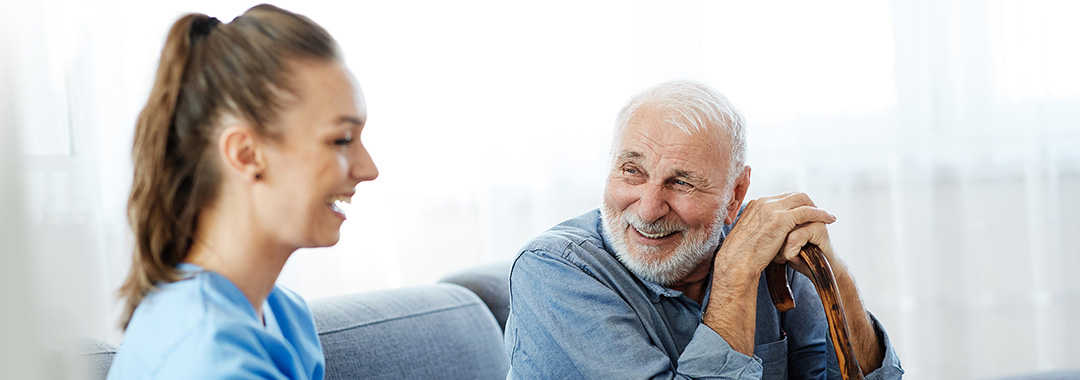 yolo-1080x380-5 A nurse sitting with an elderly man in his home